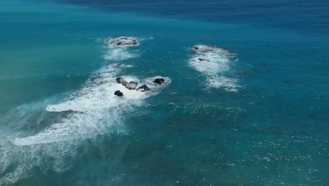 Wide-angle,-high-altitude-view-of-waves-breaking-and-crashing-over-large-rocks-near-the-shoreline