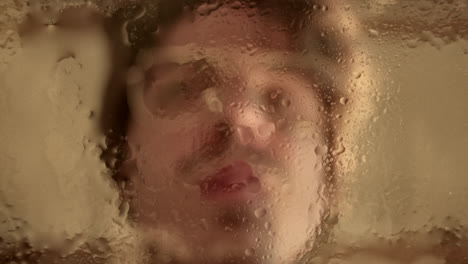 obscured face behind steamy glass with water droplets