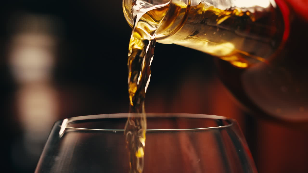 Orange or white wine bottle and glass against a sunset in a peaceful vineyard, pouring of ecological natural wine.