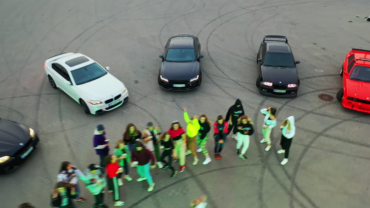 Hip hop dancers performing at the stadium for drift. Race cars are around the dancers. Top view.