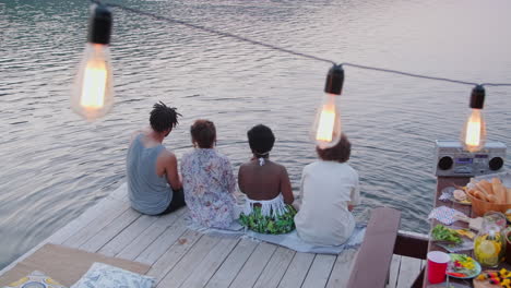 friends sitting on wooden pier and discussing lake view