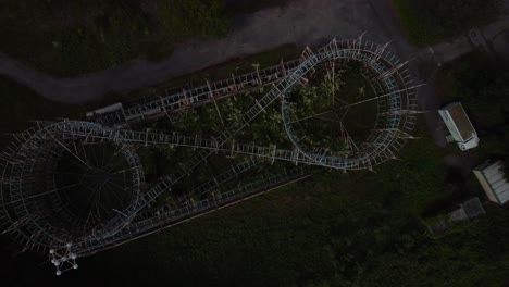 Vista-Aérea-De-Arriba-Hacia-Abajo-Del-Espeluznante-Parque-Lunar-Abandonado,-Elevándose-Por-Encima-De-La-Montaña-Rusa