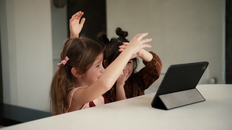Two diverse sisters using the tablet digital computer for e-learning or watching cartoons, having fun