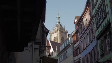 scenic view of the cathedral tower behind medieval buildings in colmar, france