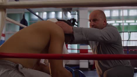 caucasian coach taking care of athlete in boxing ring