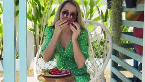 woman eating dragon fruit in a hanging chair