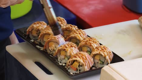 chef preparing grilled sushi rolls