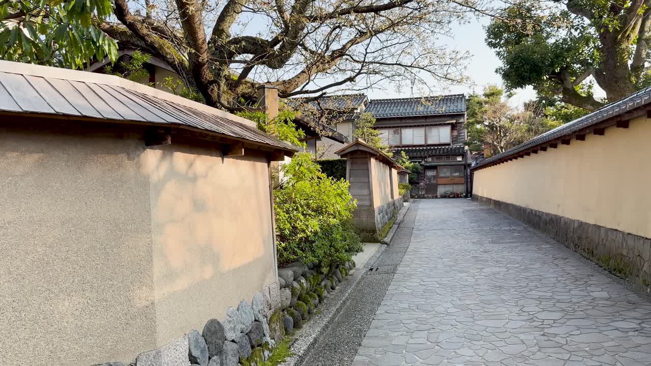 歴史的な壁と家々が並ぶ静かな日本の伝統的な路地。