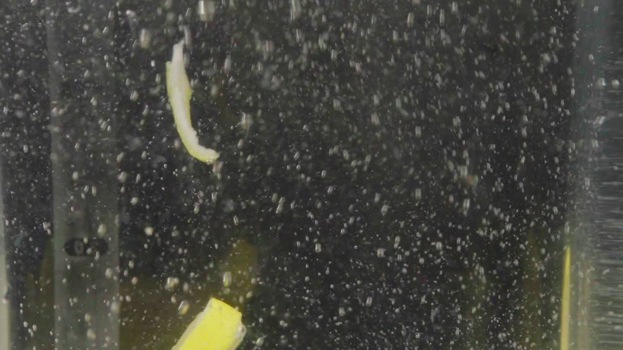 rebanadas de limón que caen en una solución acuosa clara