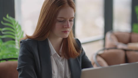 Una-Mujer-Pelirroja-Preocupada-Y-Reflexiva-Que-Trabaja-En-Una-Computadora-Portátil-Mirando-Hacia-Otro-Lado-Pensando-En-Resolver-Un-Problema-En-La-Oficina-Una-Mujer-Seria-Busca-Inspiración-Para-Tomar-Decisiones-Y-Sentir-Falta-De-Ideas