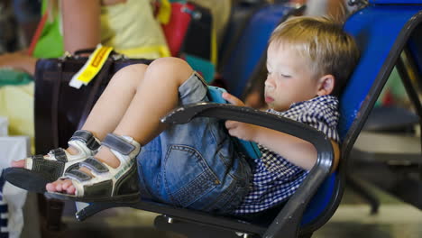 el chico se divierte con el pad en la sala de espera.