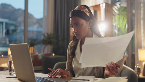 woman working on laptop with paperwork at home office