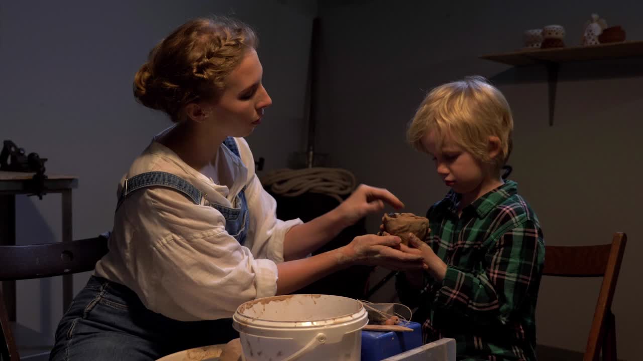 cámara lenta, la mujer ayuda al niño a esculpir en el taller
