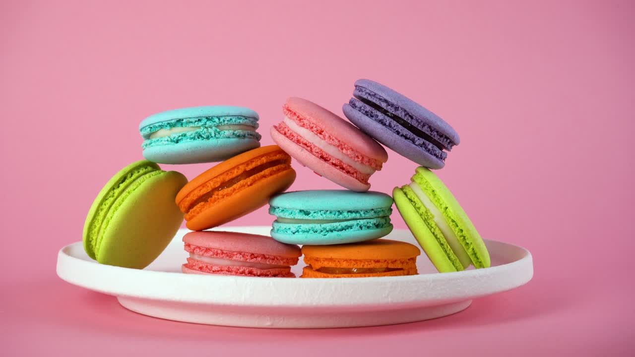 las manos de la mujer toman deliciosos macarrones franceses de colores del plato.
