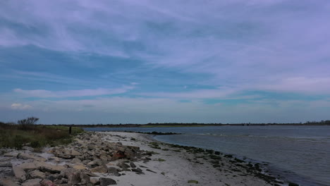 Eine-Drohnenaufnahme-Aus-Einem-Niedrigen-Winkel-Von-Einem-Leeren-Strand-An-Einem-Sonnigen-Tag