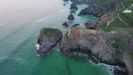 Turquoise-Blue-Sea-With-Large-Sea-Stack-Boulders-At-The-Coast---Bedruthan-Steps,-Cornwall,-UK---high-angle-shot