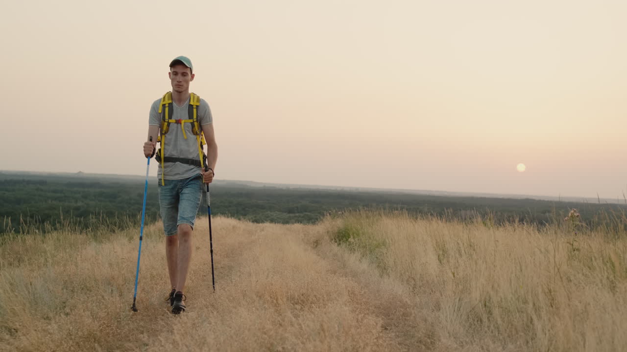 un joven adulto se dedica a caminar escandinavo con una mochila por el campo 1
