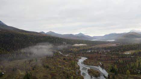 nebliges bergtal und fluss im herbst