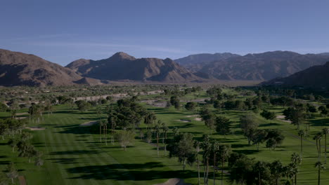 aerial view of a desert golf course with palm trees and mountains
