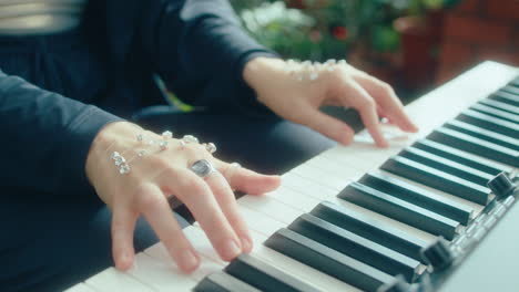 gemstone-adorned hands of female musician playing keyboard in orangery