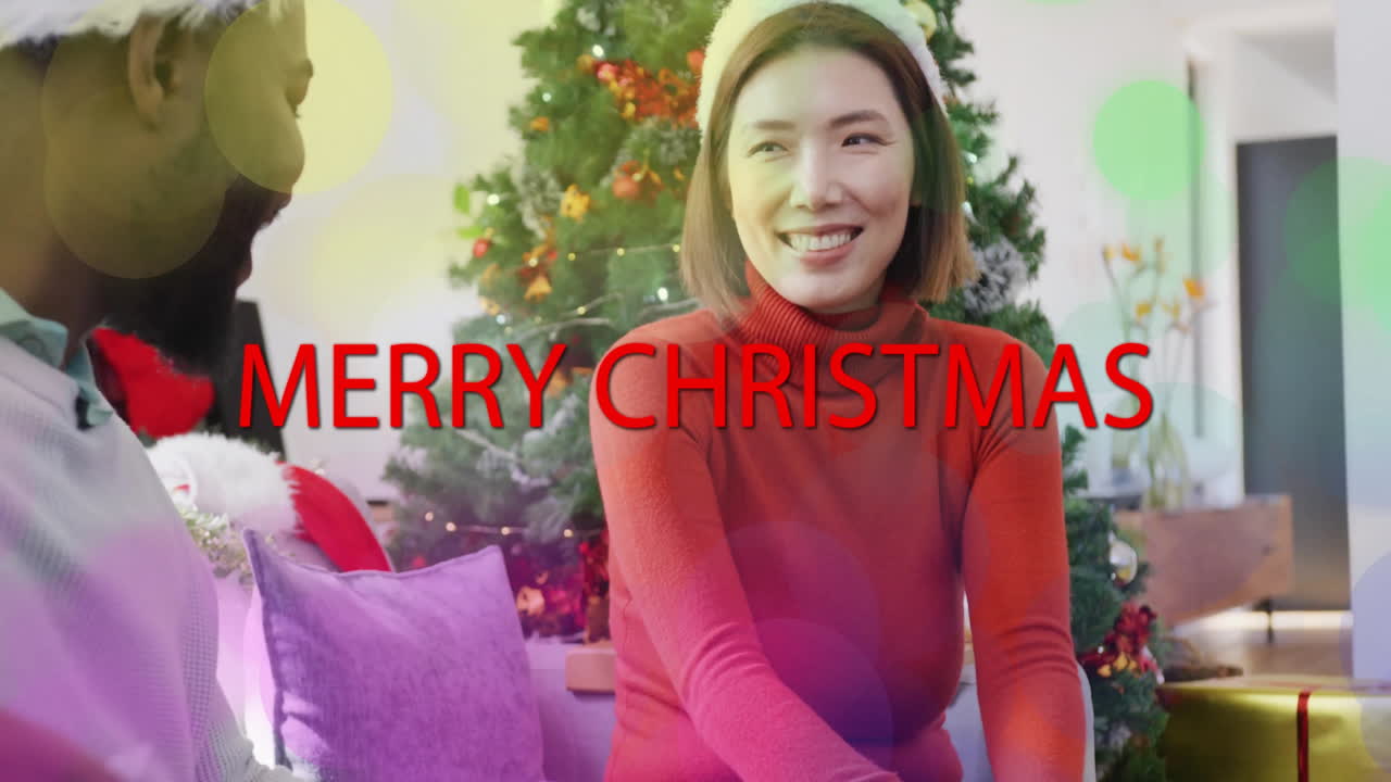 장식 된 크리스마스 트리 근처 에 미소 짓는 사람 들 위 에 메리 크리스마스 텍스트 애니메이션