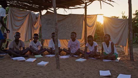 young african students studying collaboratively during golden sunset in rustic outdoor classroom, embodying community spirit and educational resilience