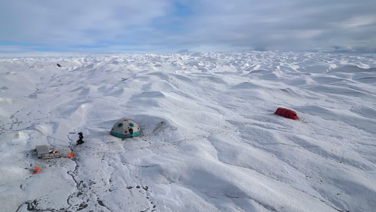 Aerial orbits large dome tent in ecotourism camp on vast ice glacier