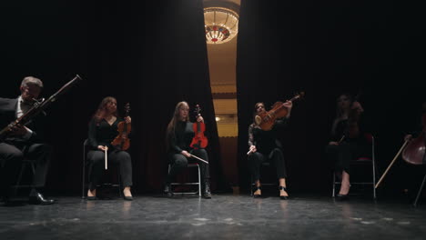 musical-ensemble-of-string-and-wind-instrument-on-scene-of-old-opera-house-curtain-is-opening