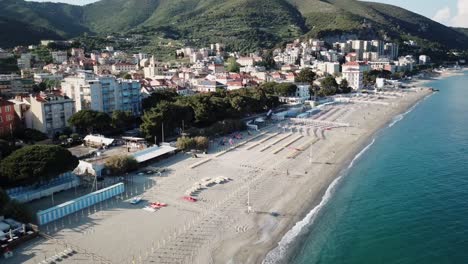 Toma-Panorámica-De-La-Costa-Mediterránea,-Playa-De-Arena-Y-Un-Pueblo