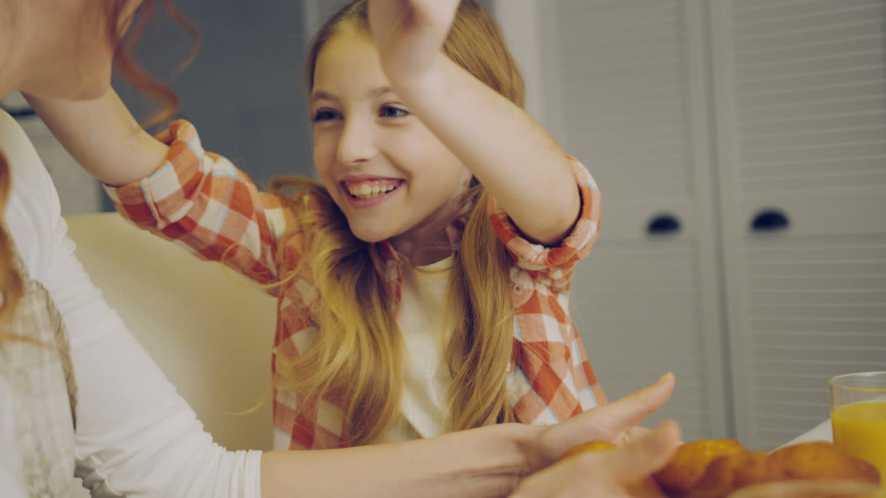 딸과 예쁜 소녀가 그녀를 포옹하는 테이블에 마핀을 놓고 있는 어머니의 클로즈업. 초상화 촬영. 실내