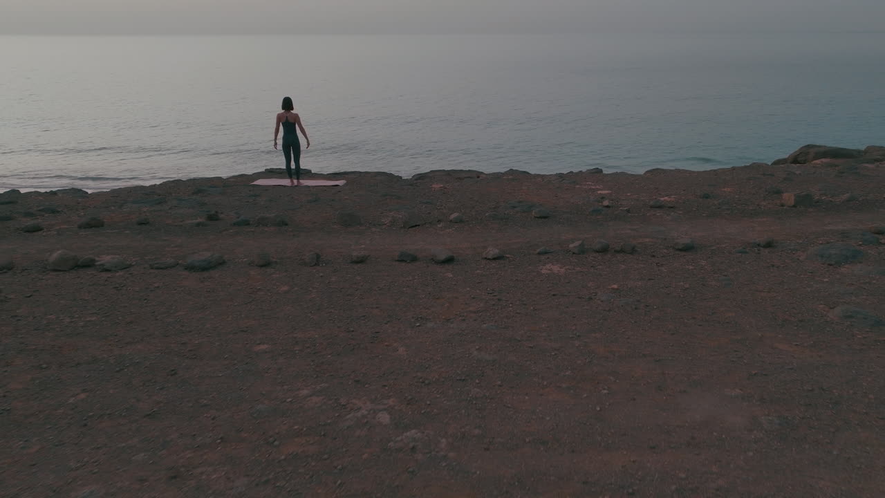 mujer practicando yoga en una playa al amanecer o al atardecer