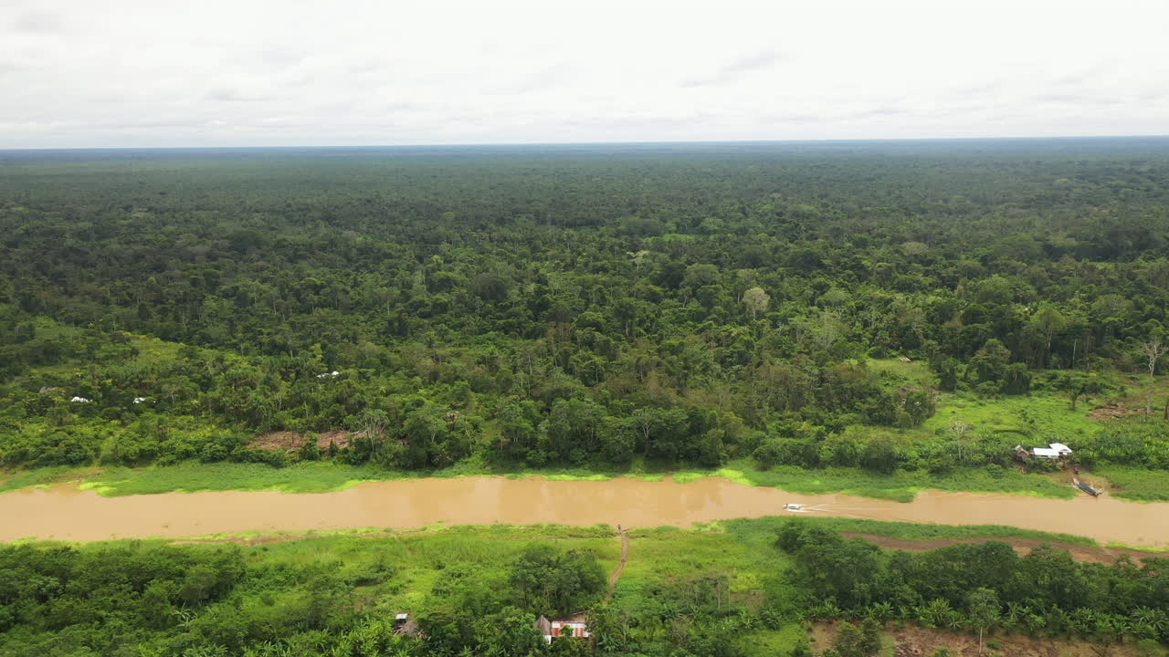 tiro de dron giratorio ancho con un bote en el río amazonas y la selva tropical que rodea el río en perú