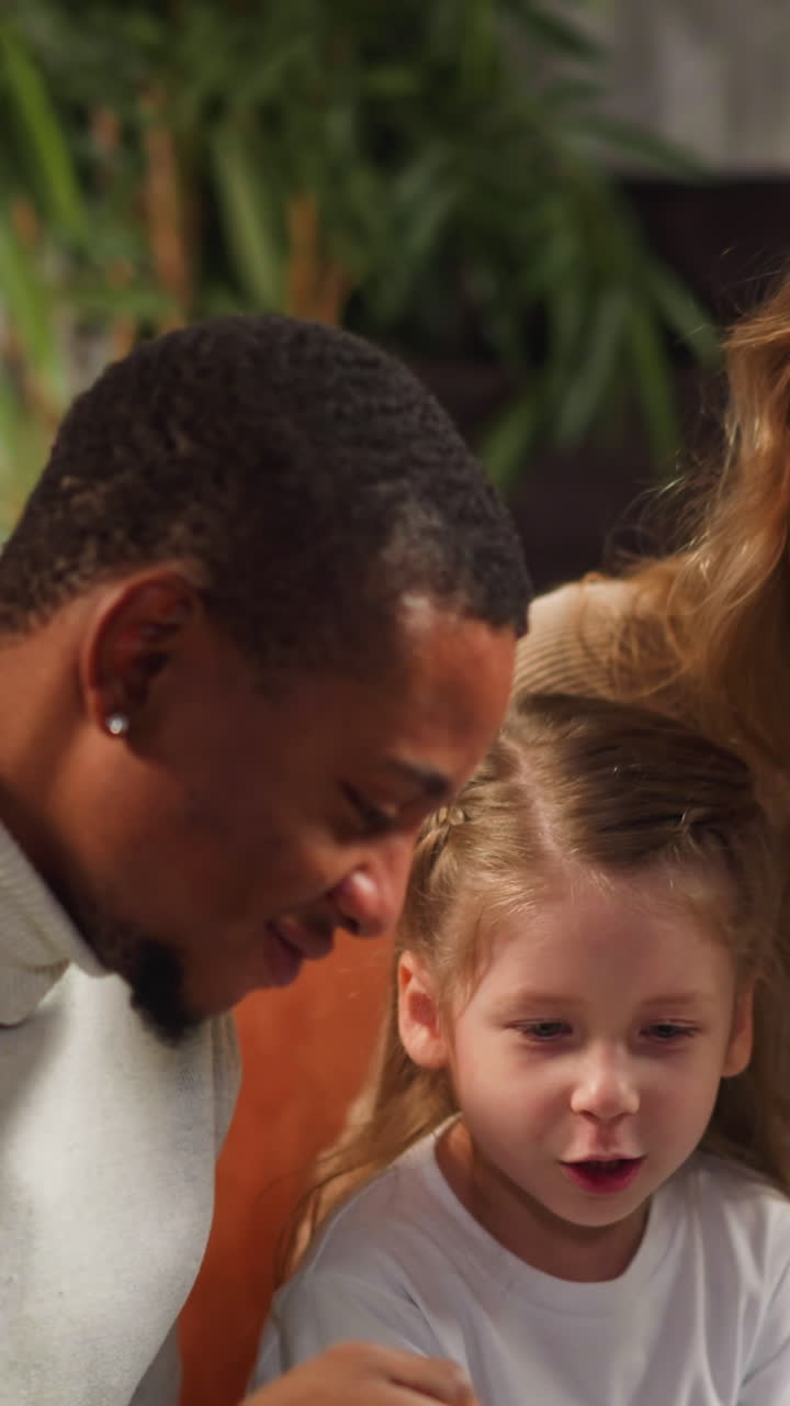 Little girl asks question about family to mother colleague looking at vintage photo album in cozy living room during visit closeup slow motion
