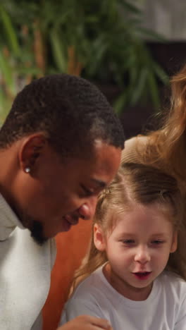 little girl asks question about family to mother colleague looking at vintage photo album in cozy living room during visit closeup slow motion
