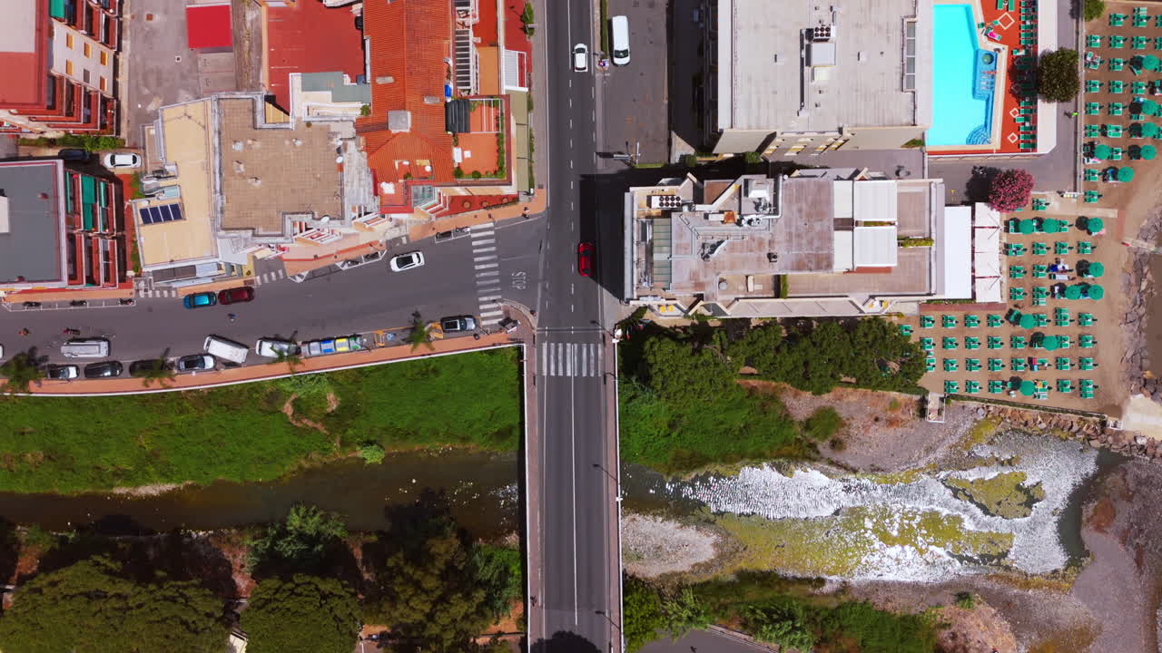 The drone captures a full top-down shot over a coastal road in Varigotti, following a car driving during sunset