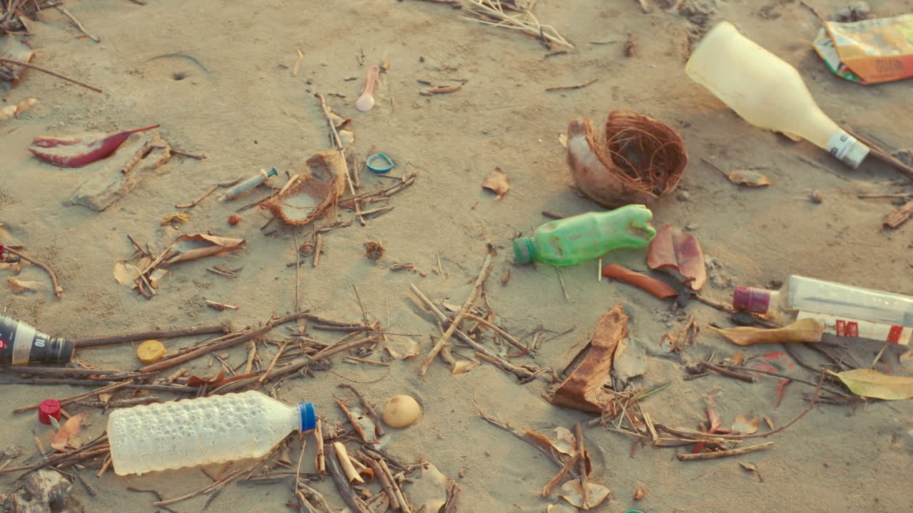 Spiaggia piena di rifiuti con plastica, bottiglie e spazzatura, che mostra l'impatto dell'inquinamento