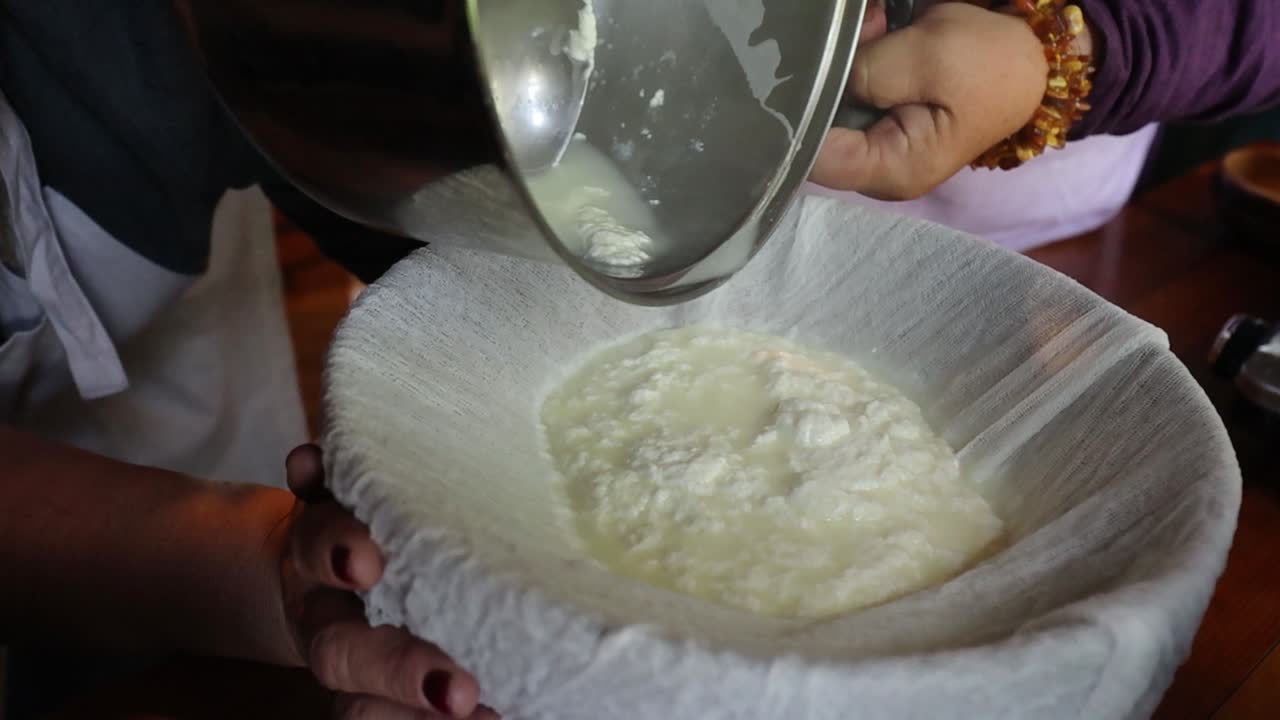 Curdled milk being strained through cheesecloth, separating curds and whey in the process of making homemade cheese or yogurt