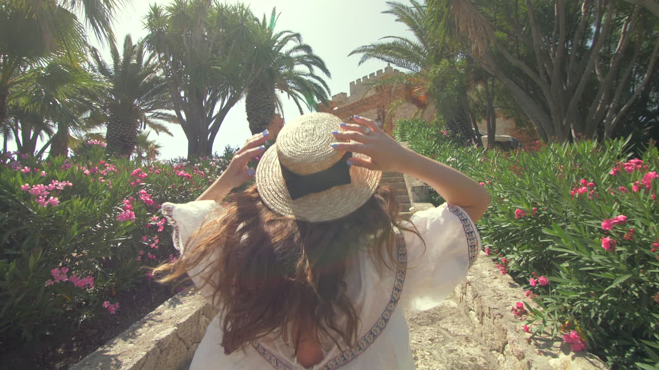 mujer subiendo escaleras de piedra con palmeras y flores