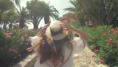 woman walking up stone stairs with palm trees and flowers