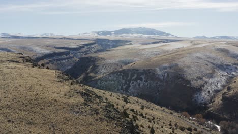 a drone flies over a grassy ridge in rural idaho with snow