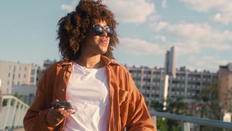 Black-woman-walking-across-the-bridge-and-looking-at-her-mobile-phone