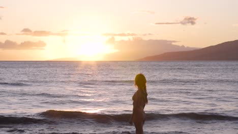 caucasian woman watching the sunset from a maui beach.