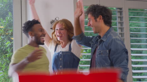 Multi-Cultural-Group-Of-Friends-Playing-Game-At-Home-Together-Throwing-Ball-Into-Paper-Cup