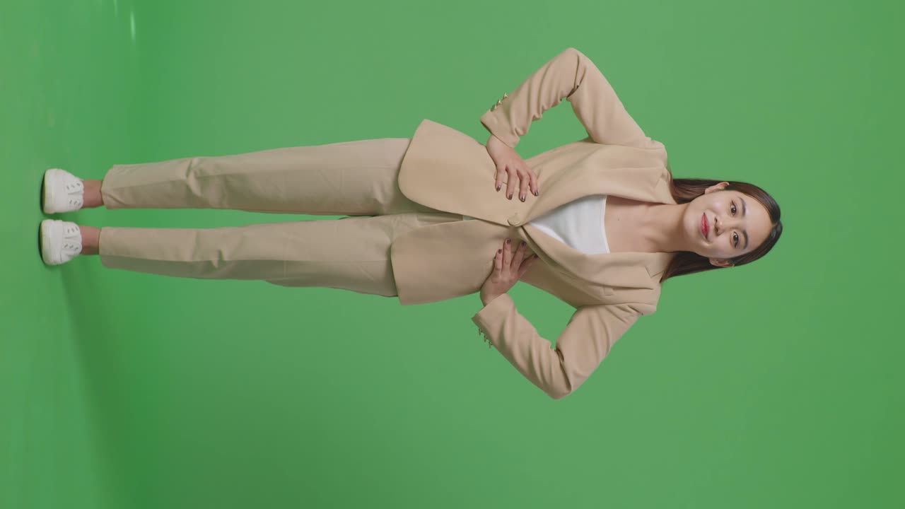 스튜디오의 녹색 스크린 배경에서 따뜻하게 미소 짓는 아시아 사업가의 몸이 가득 차 있습니다.