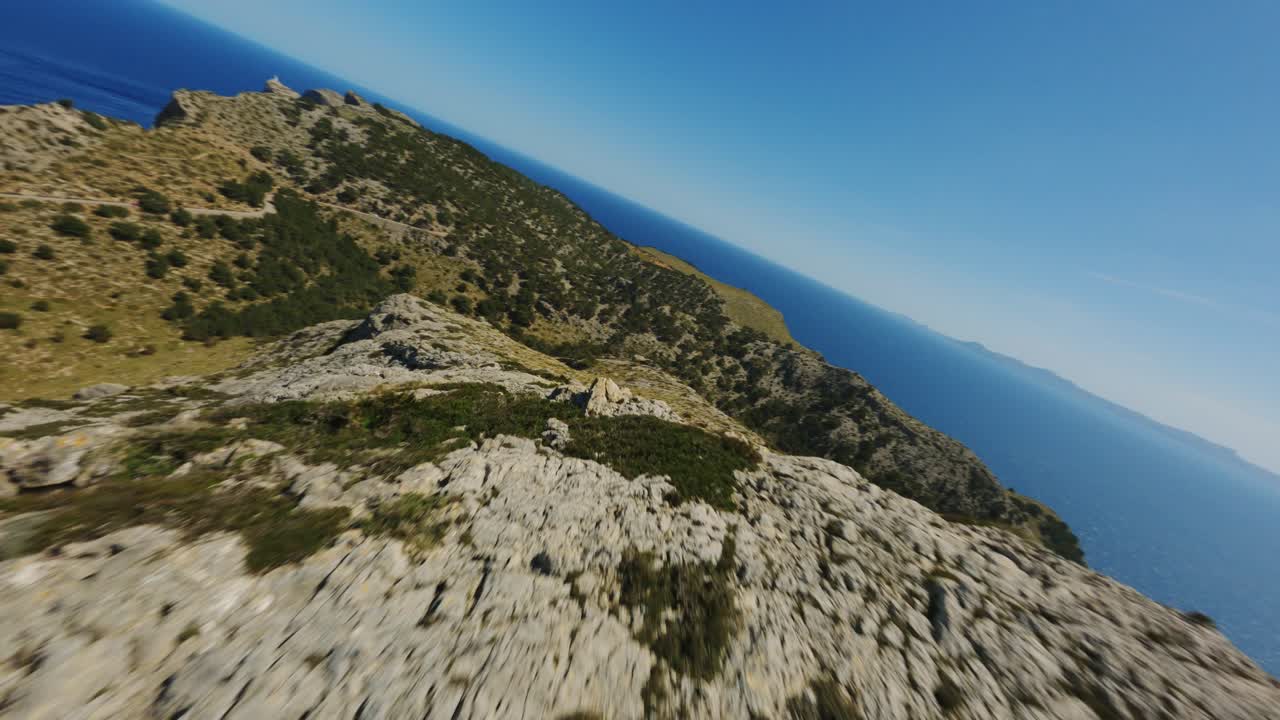 FPV Drone flying over mountain peek diving down the hill and flying closely over the heads of mountain goats in Mallorca