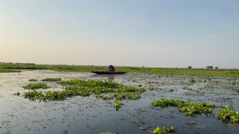 Pareja-Romántica-Disfrutando-De-La-Vista-Del-Atardecer-Desde-Un-Bote-De-Madera-En-El-Pantano-En-Bortirbil,-Bengala-Occidental