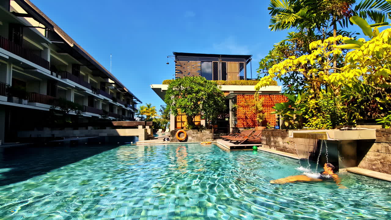 Shot of a resort with people relaxing at swimming pool during daytime in Indonesia