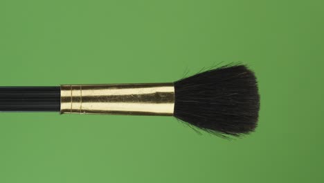 horizontal rotation of makeup brush, on green screen. close-up.