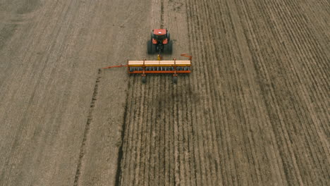 AERIAL---Harvester-tractor-cultivating-the-land,-field-at-dawn,-lowering-tilt-up
