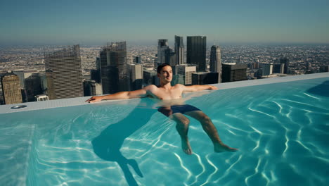 Man relaxing in a rooftop infinity pool with a city skyline view
